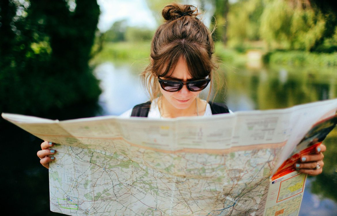 Une femme avec des lunettes de soleil lis une carte routière