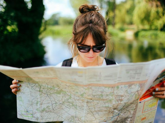 Une femme avec des lunettes de soleil lis une carte routière