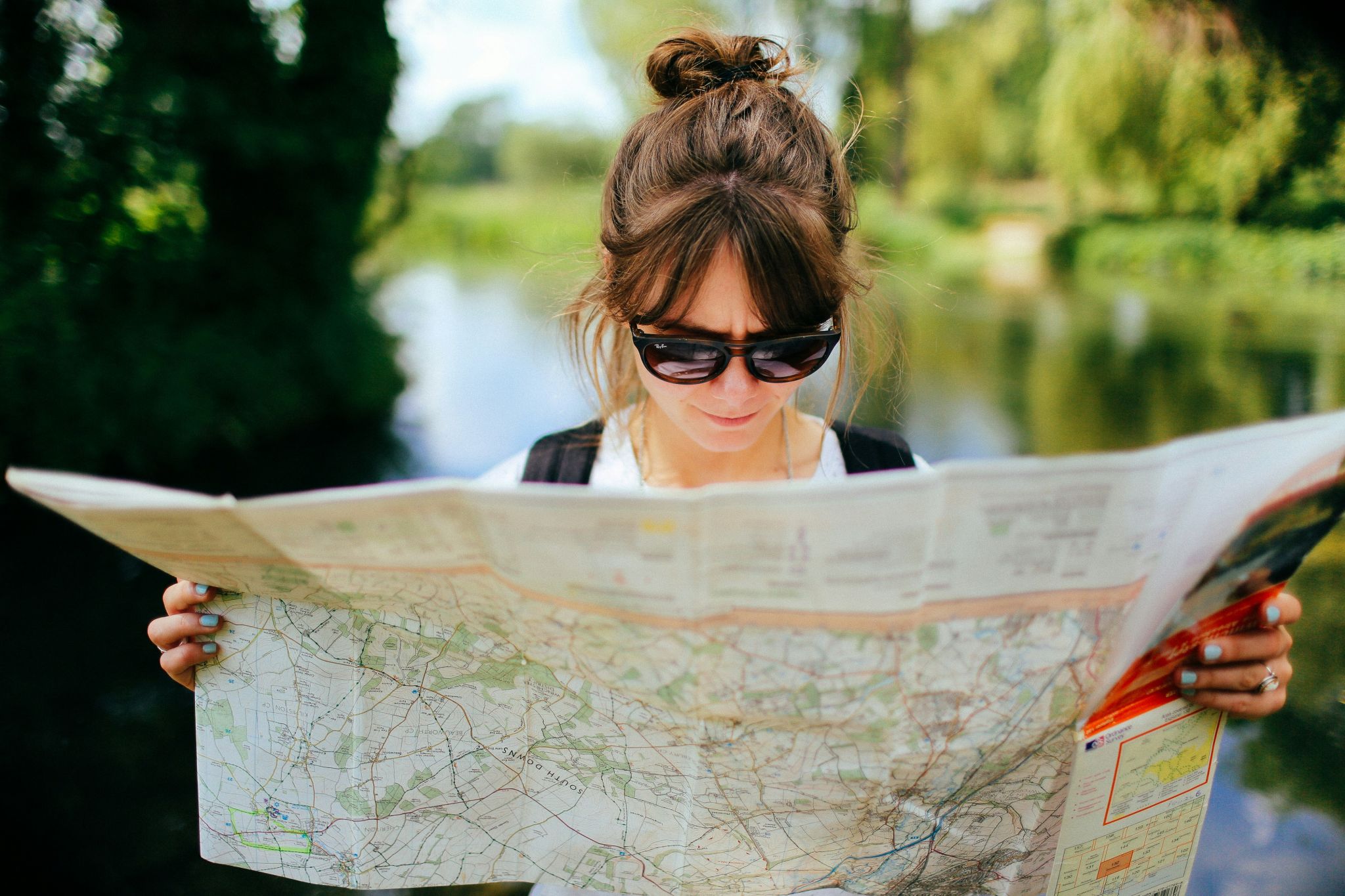 Une femme avec des lunettes de soleil lis une carte routière