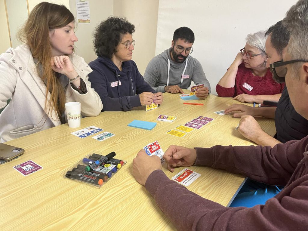 Des personnes assises autour d'une table jouent à un jeu de carte Stresss