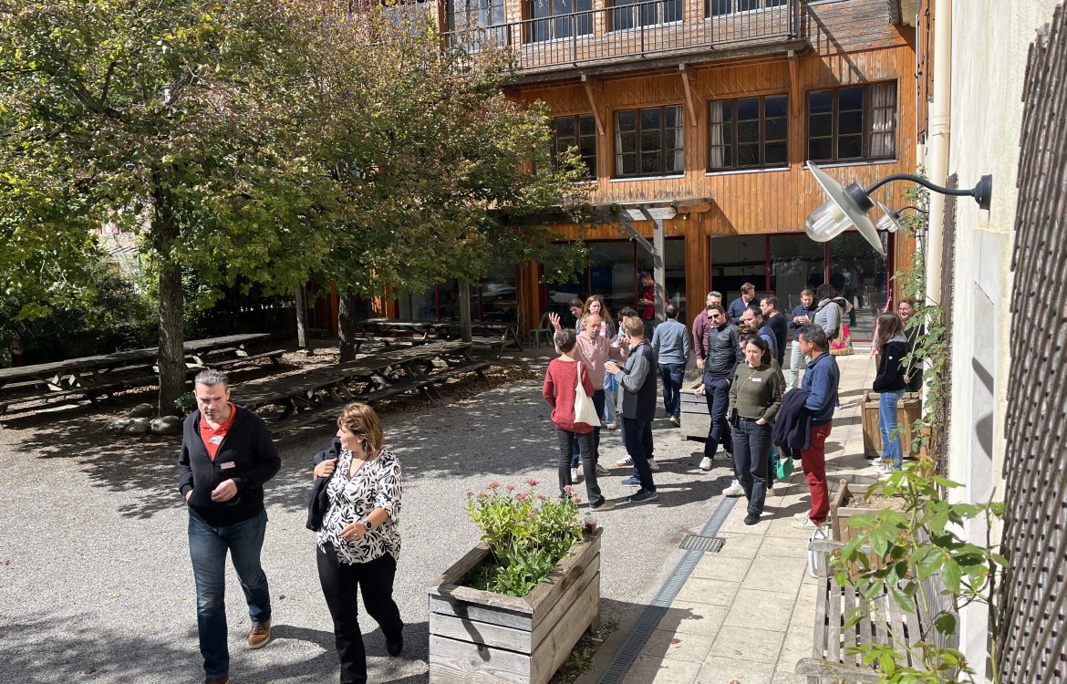 Des personnes dans la cour d'un bâtiment marchent pour rejoindre un atelier