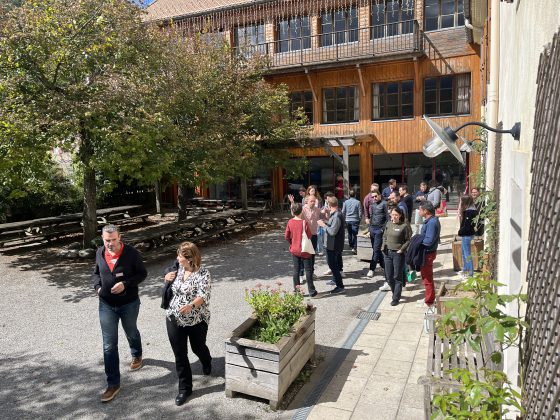 Des personnes dans la cour d'un bâtiment marchent pour rejoindre un atelier